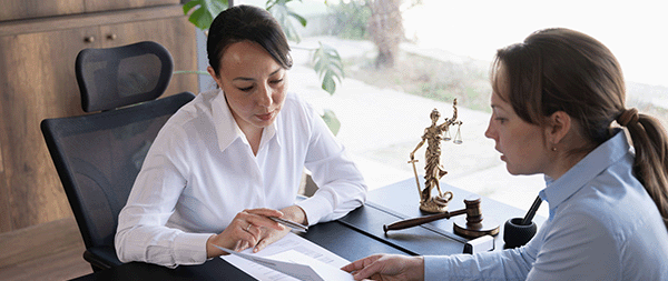 Two women consulting over a document across a desk