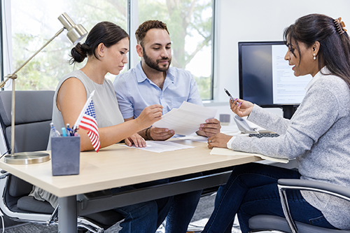 A couple sits at a desk discussing their taxes with a tax professional.