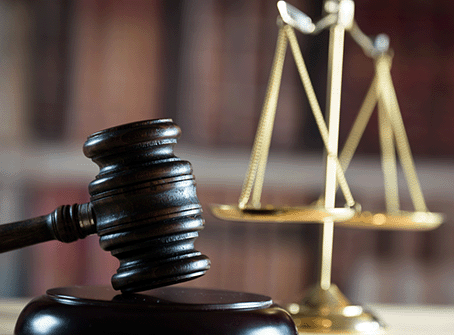 Judge's gavel and justice scales on a desk with books.