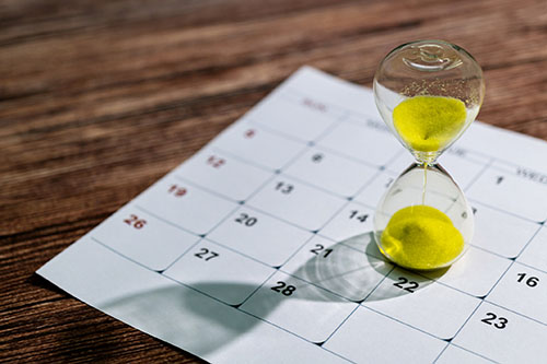 An hourglass sitting atop a monthly calendar