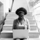 Woman sitting on steps and working on laptop computer